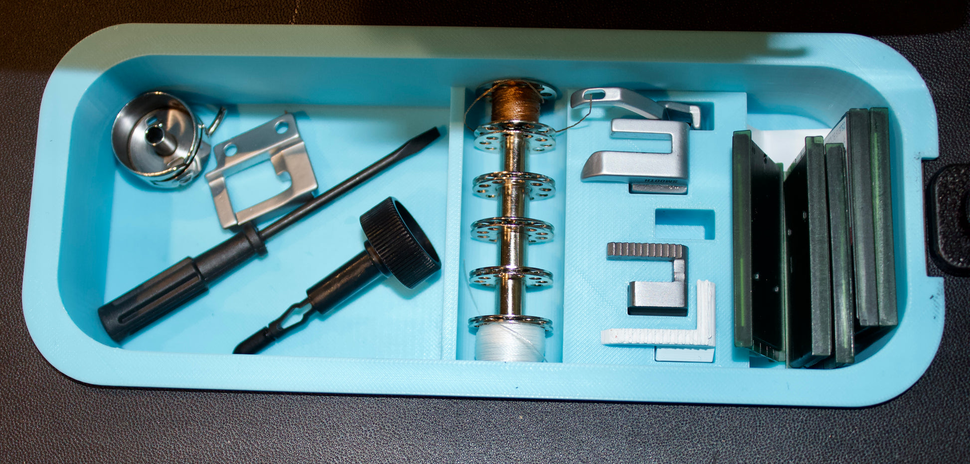 Set of tools and components on a blue tray against a black background