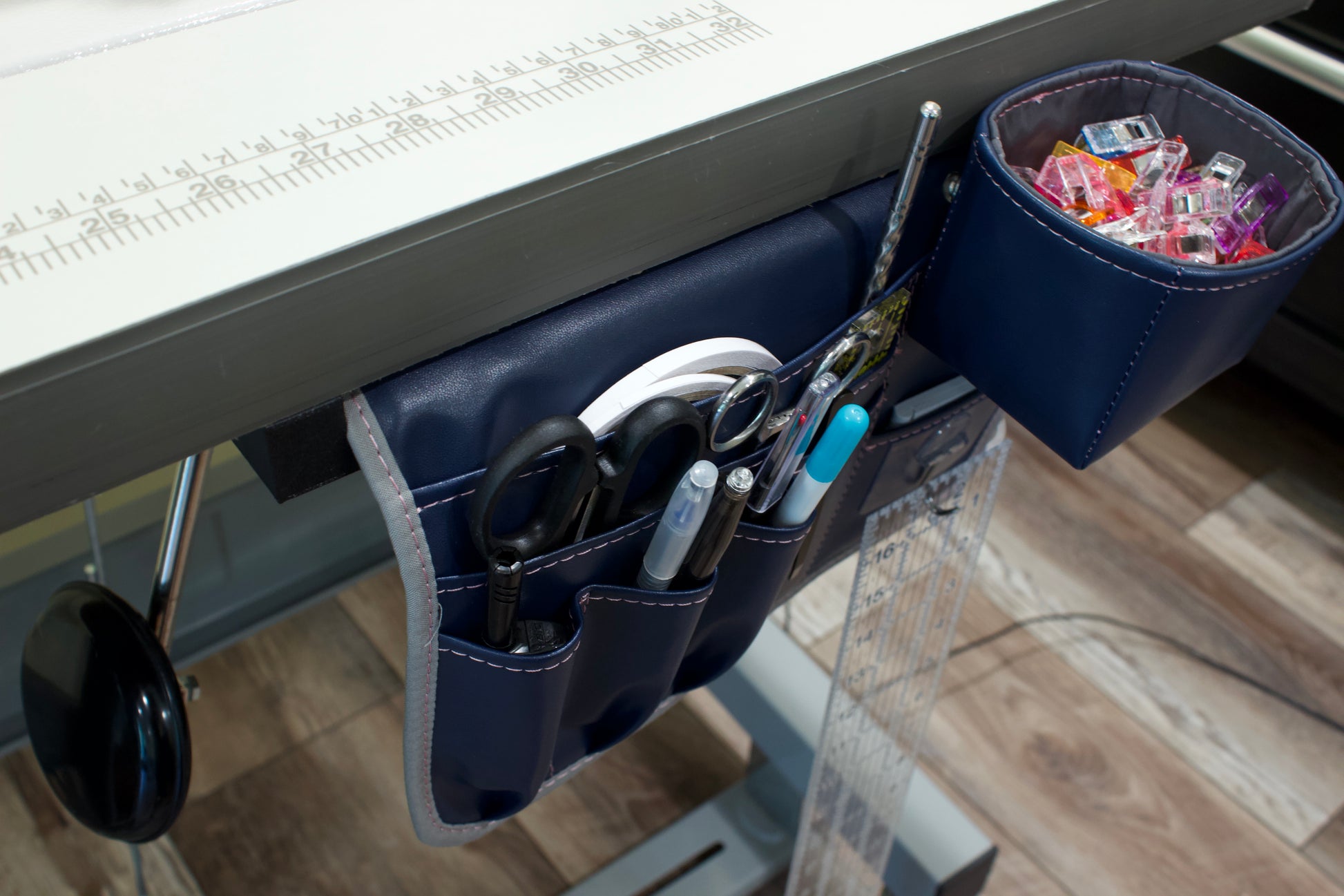 Molly Caddy Navy blue under-desk organizer with sewing items on a desk.