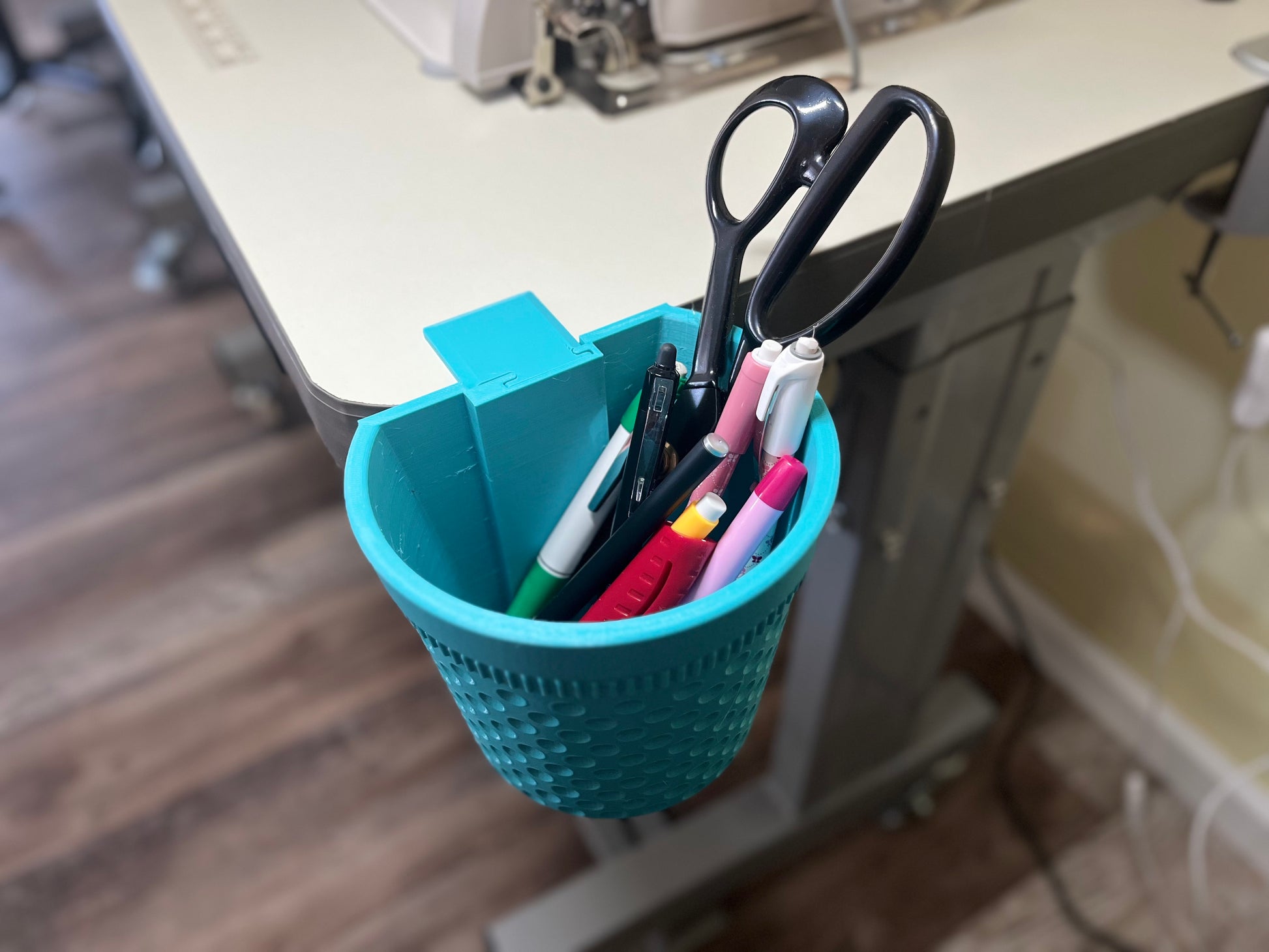 Blue thimble-shaped container bin with pens and scissors inside